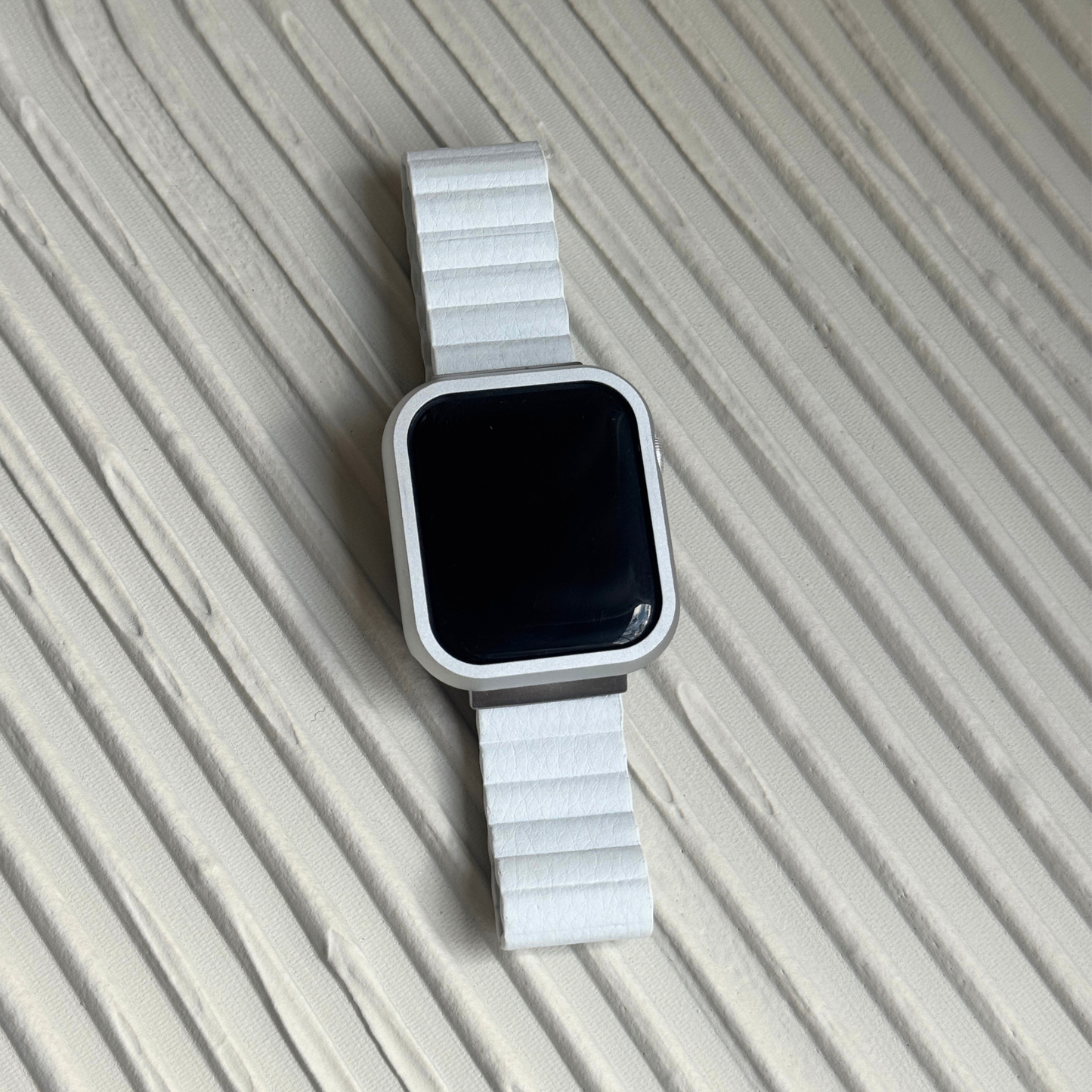 Smartwatch with a white band on a textured beige surface with a Metal stainless steel apple watch case cover