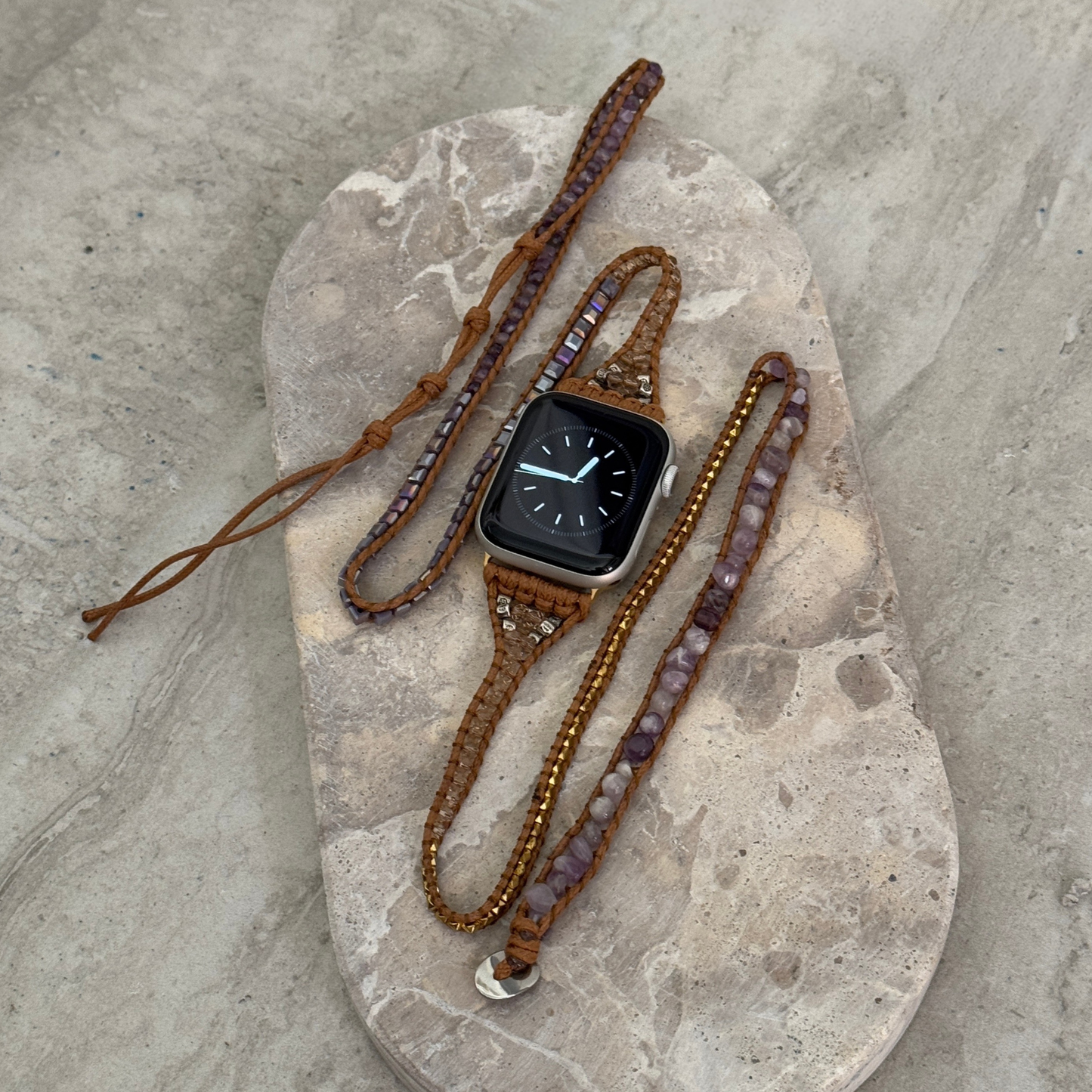 Smartwatch with a decorative brown strap on a stone surface