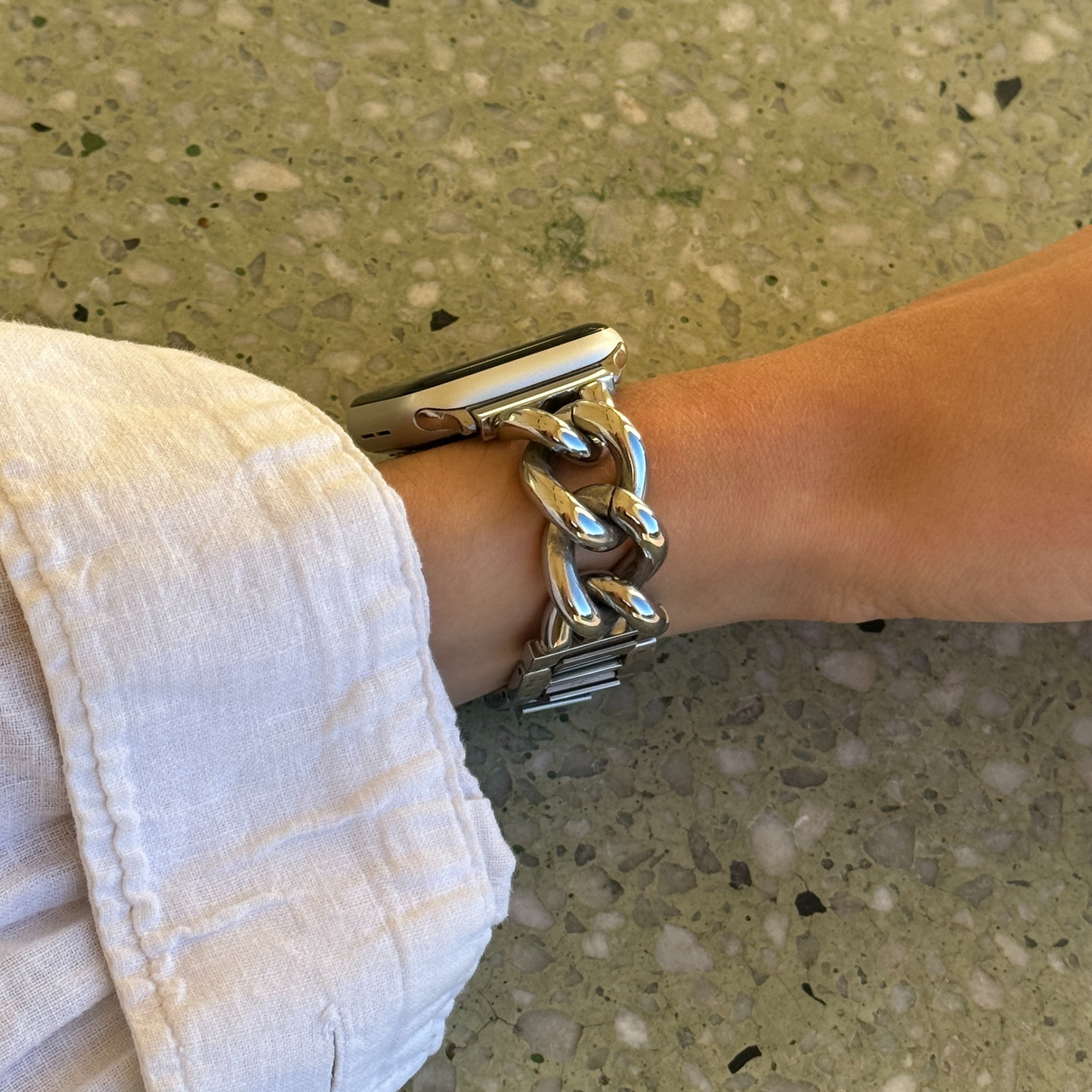Silver chain bracelet on a wrist with a neutral background