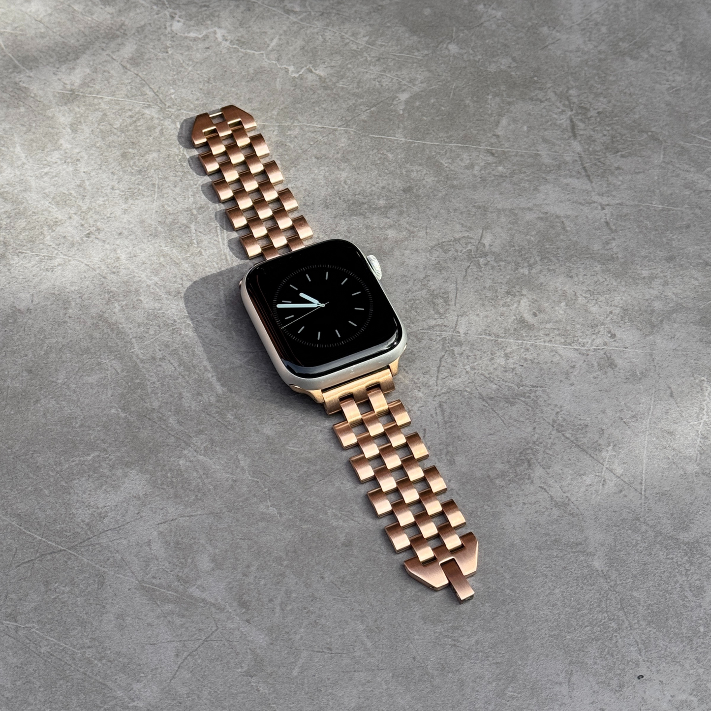 Smartwatch with a rose gold metal band on a gray surface