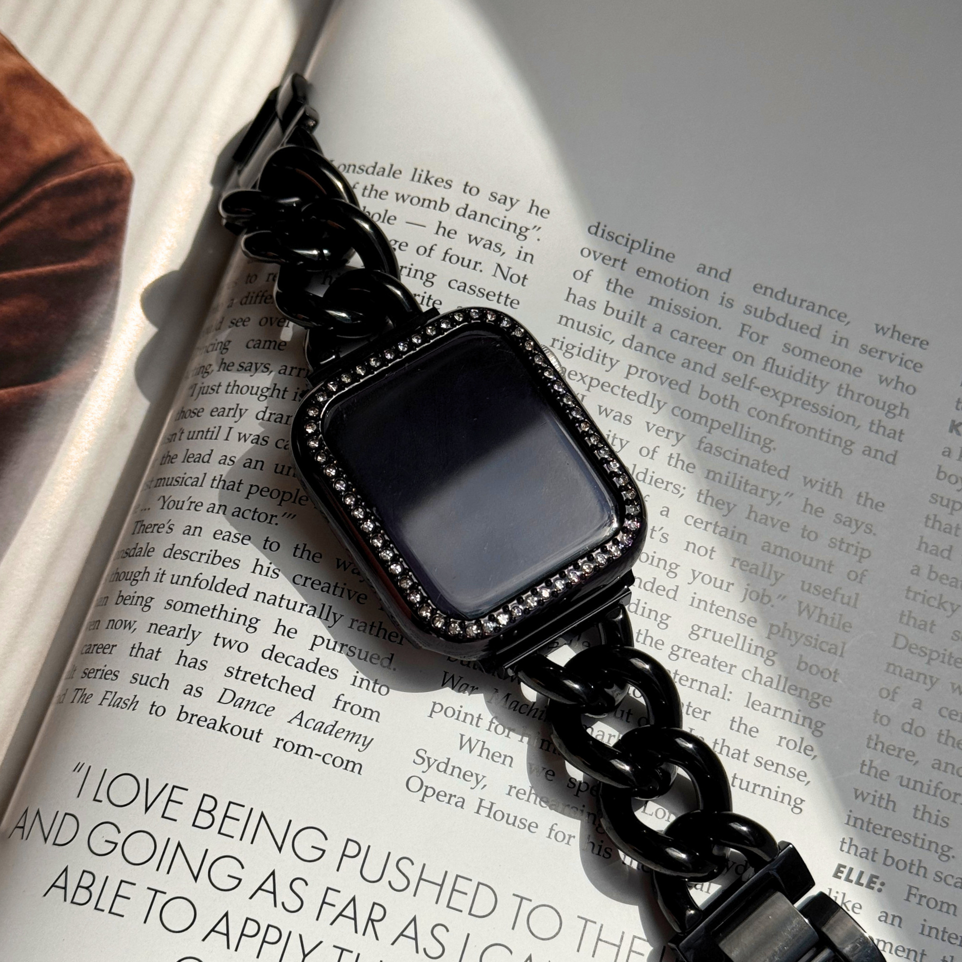 Black chain-strap smartwatch on an open book, Gold rhinestone apple watch case