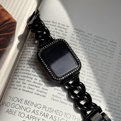 Black chain-strap smartwatch on an open book, Gold rhinestone apple watch case