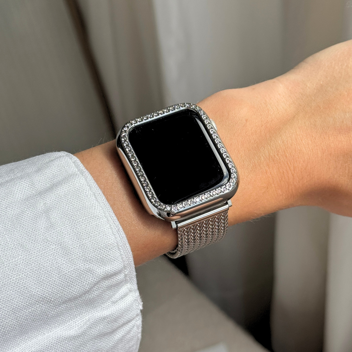 Smartwatch with a decorative band on a wrist against a neutral background with a Gold rhinestone apple watch case