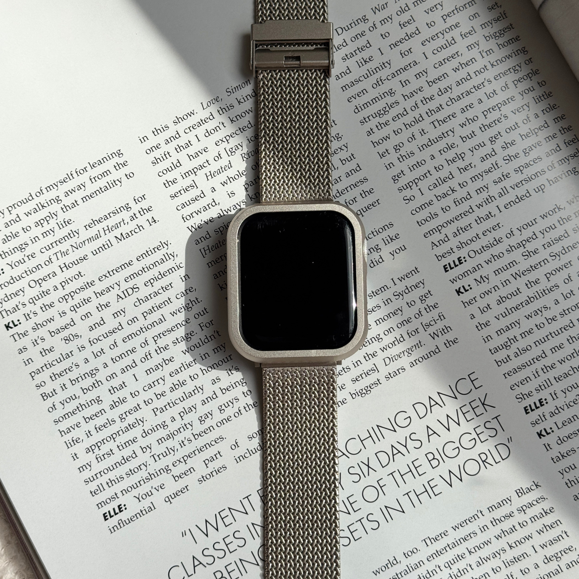 Smartwatch with a beige band on an open book with a Metal stainless steel apple watch case cover