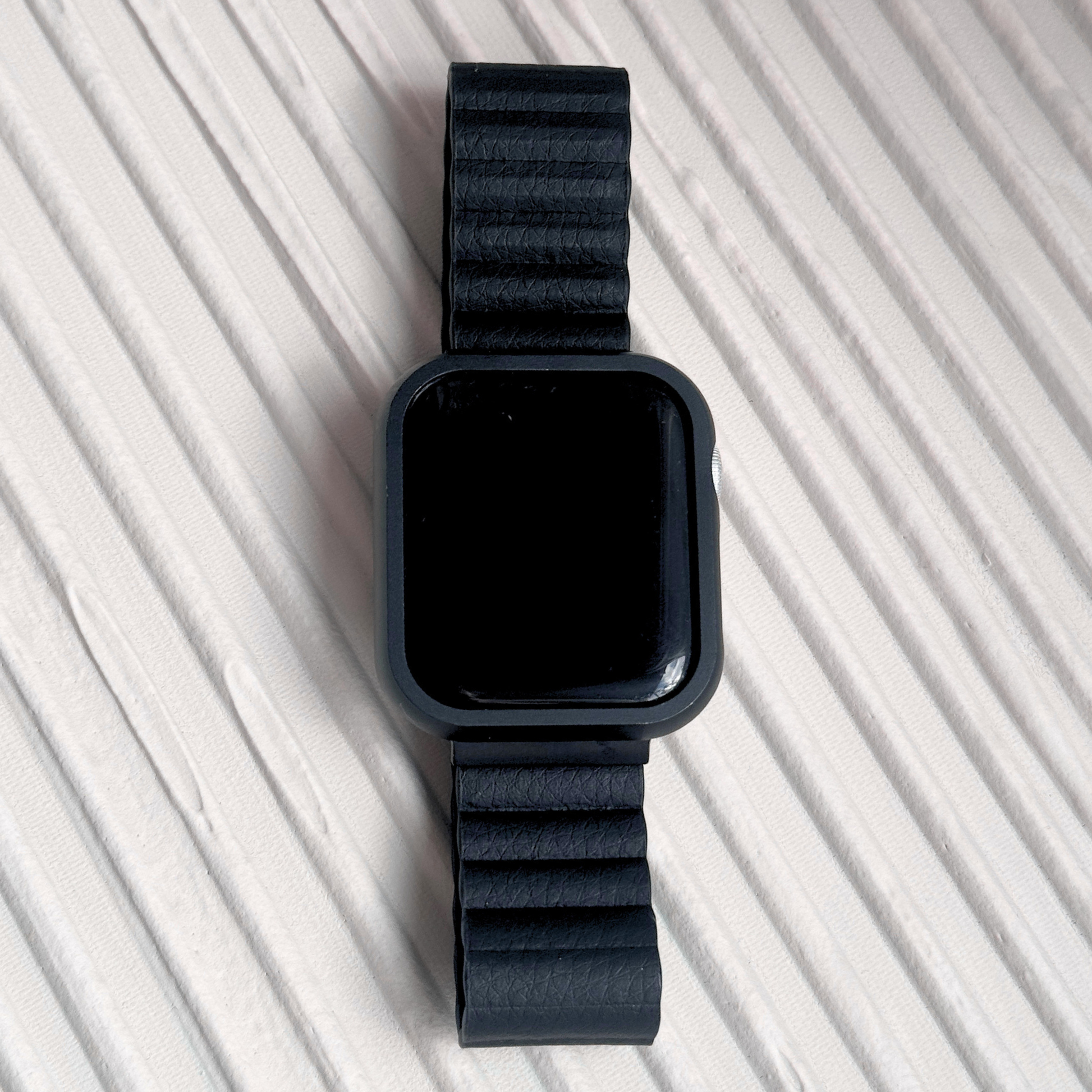 Black smartwatch with a matching band on a light gray background with a Metal stainless steel apple watch case cover