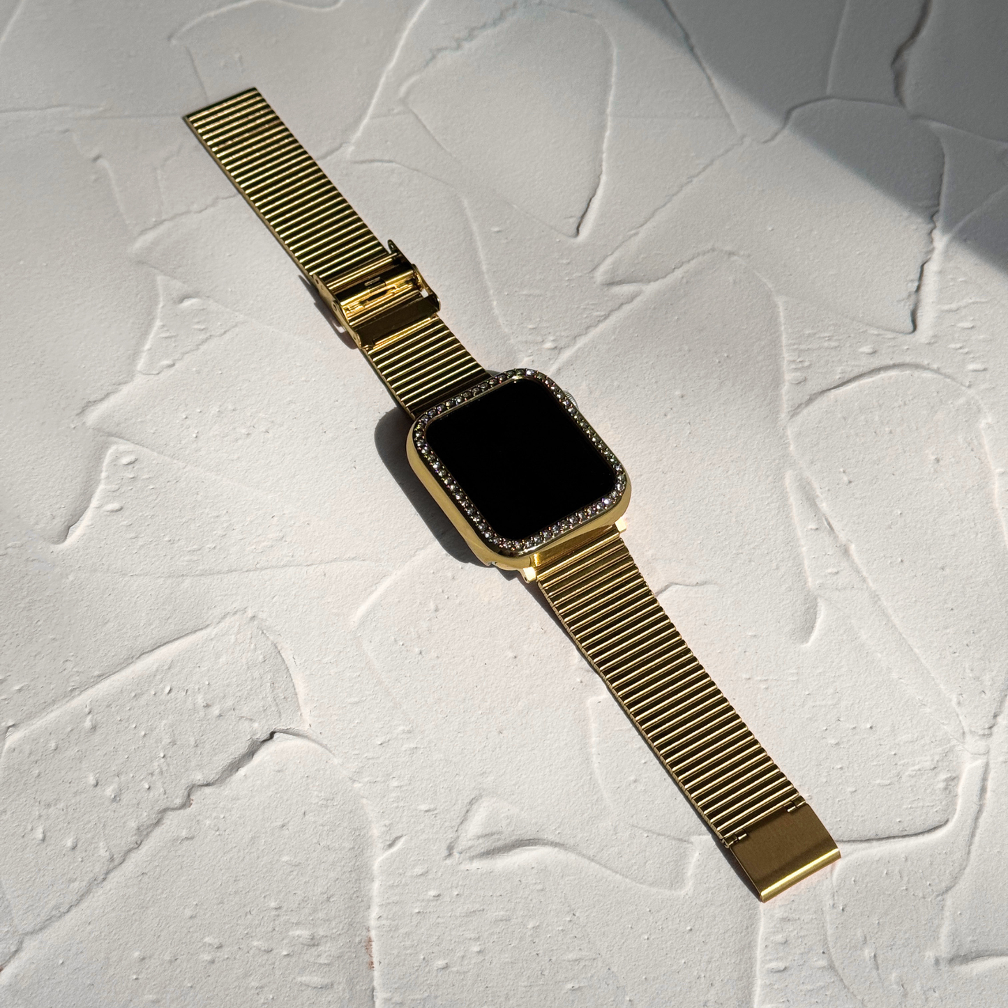 Gold smartwatch with a textured white background with a Gold rhinestone apple watch case