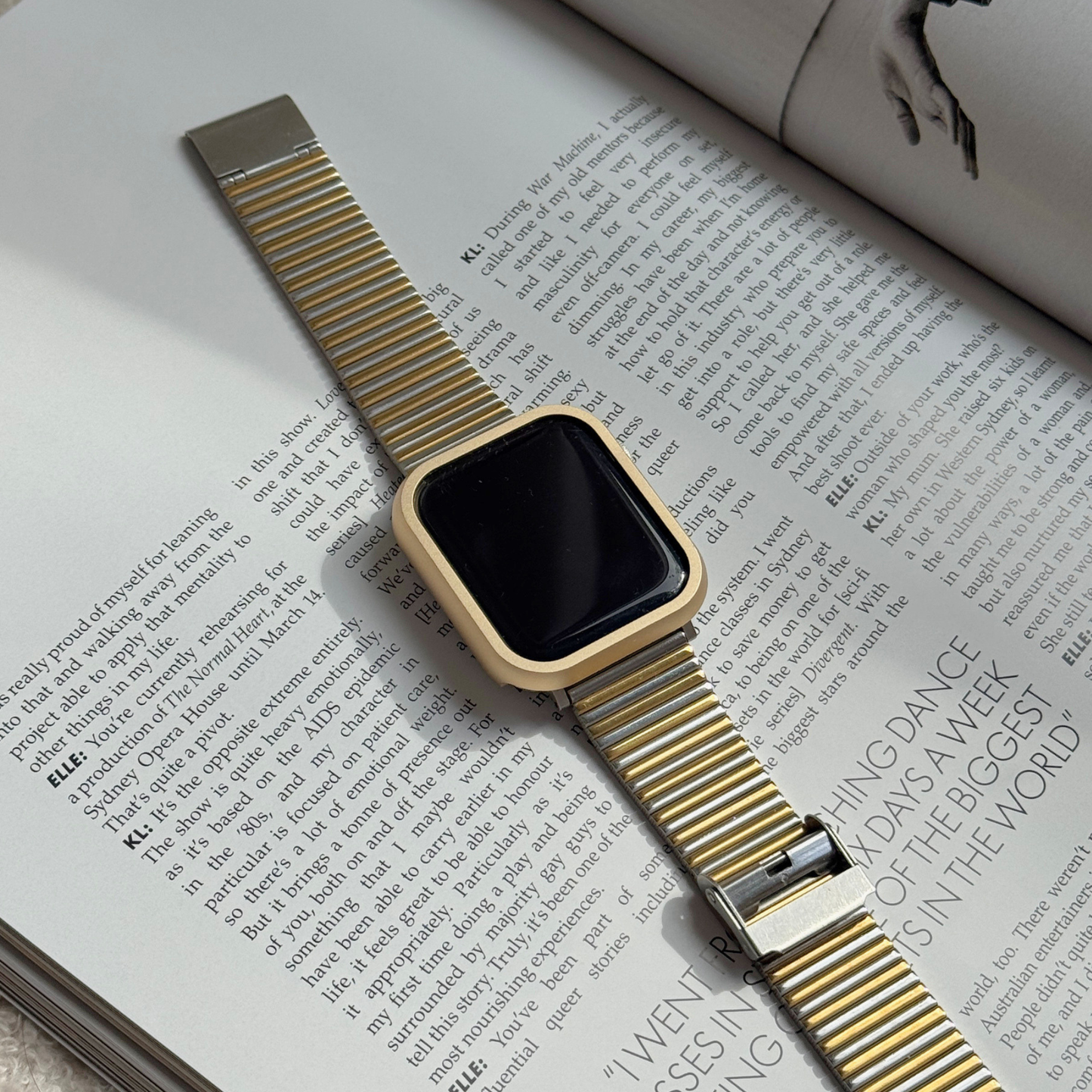 Gold smartwatch on an open magazine with a Metal stainless steel apple watch case cover on it