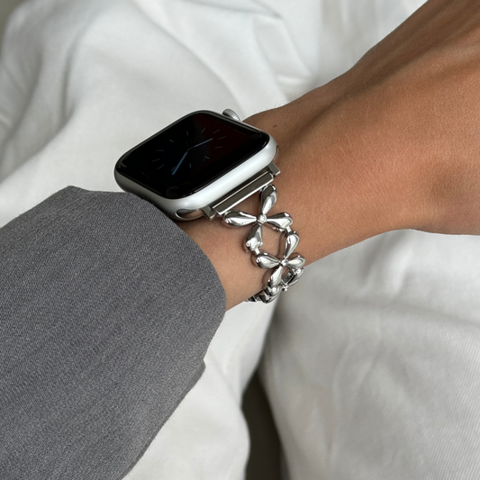 A gold-colored metal Apple Watch band with a unique floral link design, displayed on a white background.