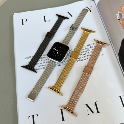 Black, silver, gold and rose gold woven mesh Apple Watch bands laid out on a magazine, stainless steel straps for Apple Watch 38mm to 49mm