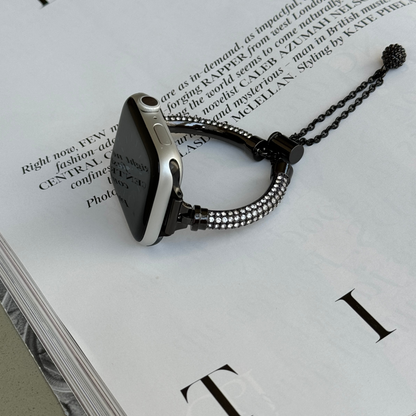 Black rhinestone Apple Watch band lying flat on an open magazine, metal bracelet for Apple Watch 38mm to 49mm