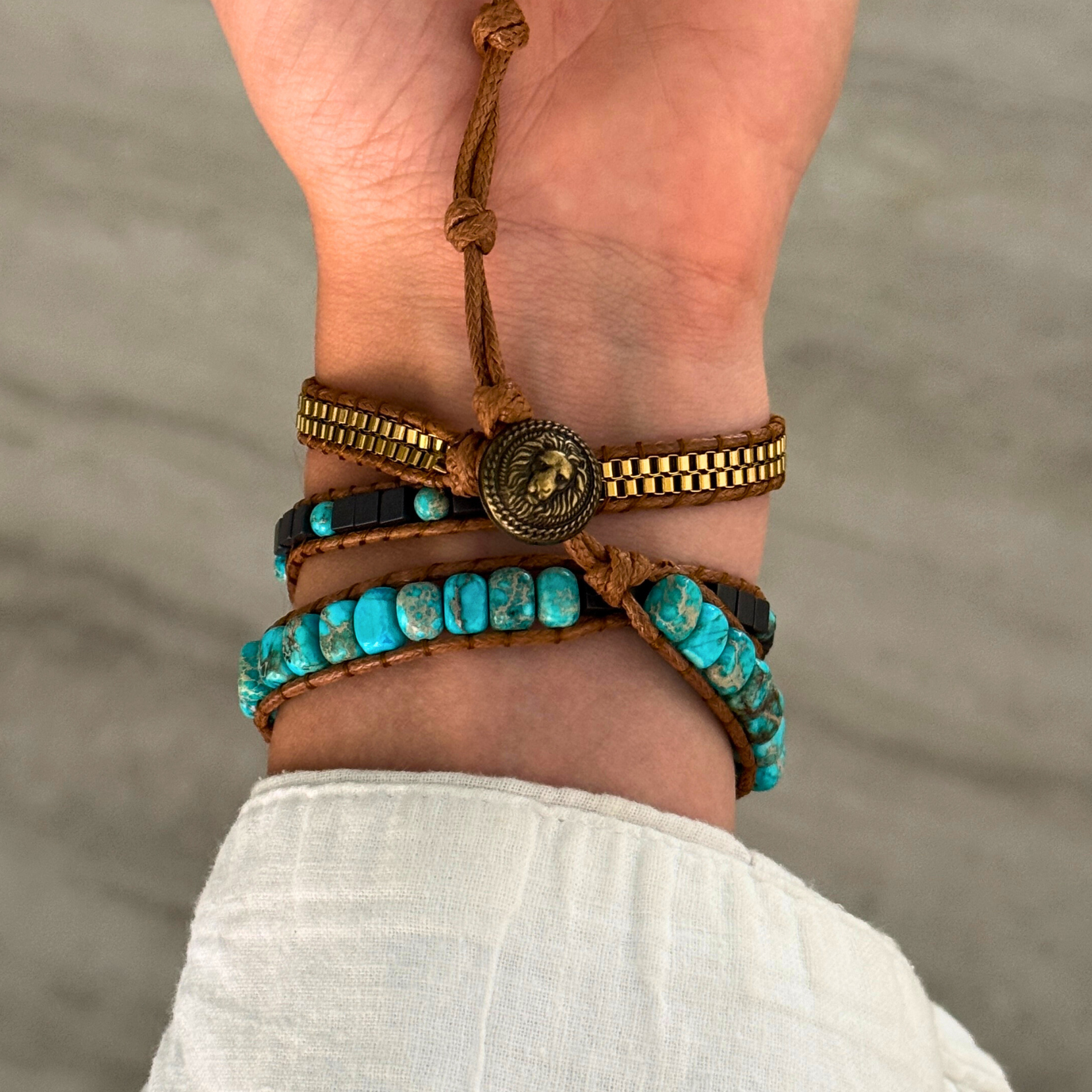 Close-up of a wrist wearing multiple bracelets with a neutral background