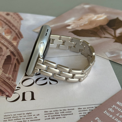 Starlight slim link Apple Watch band lying flat on pink printed papers, metal bracelet for Apple Watch 38mm to 49mm