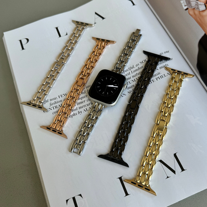 Silver, rose gold, starlight, black and gold slim link Apple Watch bands laid out on a magazine, metal straps for Apple Watch 38mm to 49mm