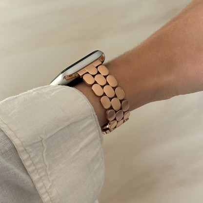 Rose gold bracelet on a wrist with a neutral background