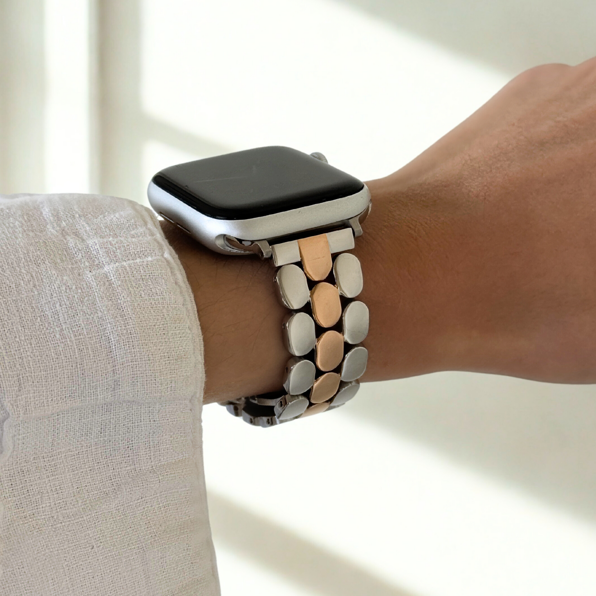 Smartwatch with a decorative band on a wrist against a neutral background