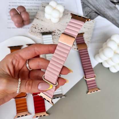 Hand holding a pink and gold watch band with a blurred background