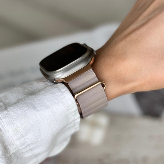 Smartwatch with a pink band on a person's wrist, wearing a white shirt.