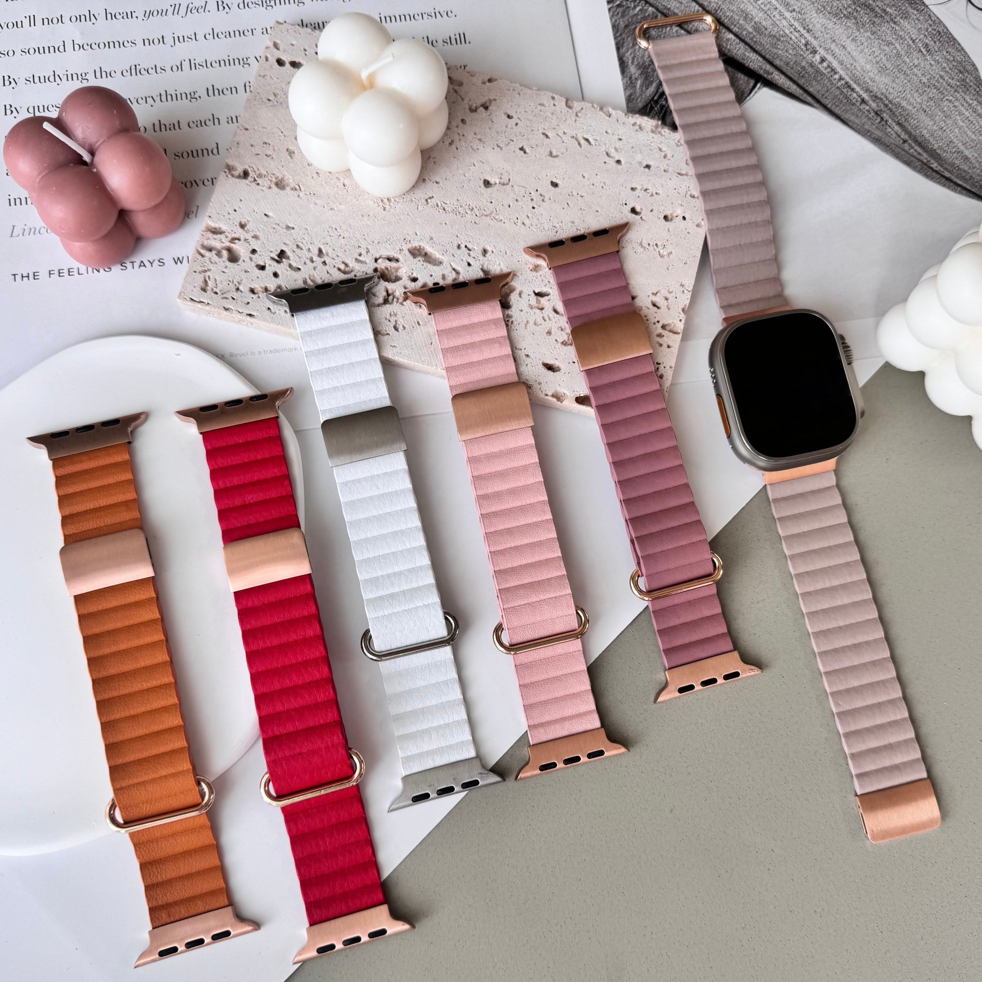 Set of colorful watch straps on a surface with a magazine and flowers.