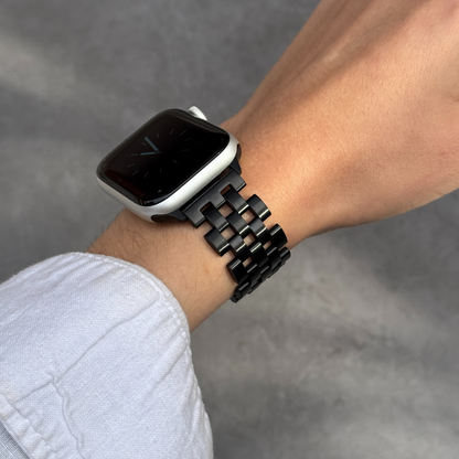 Smartwatch with a black metal band on a wrist against a gray background