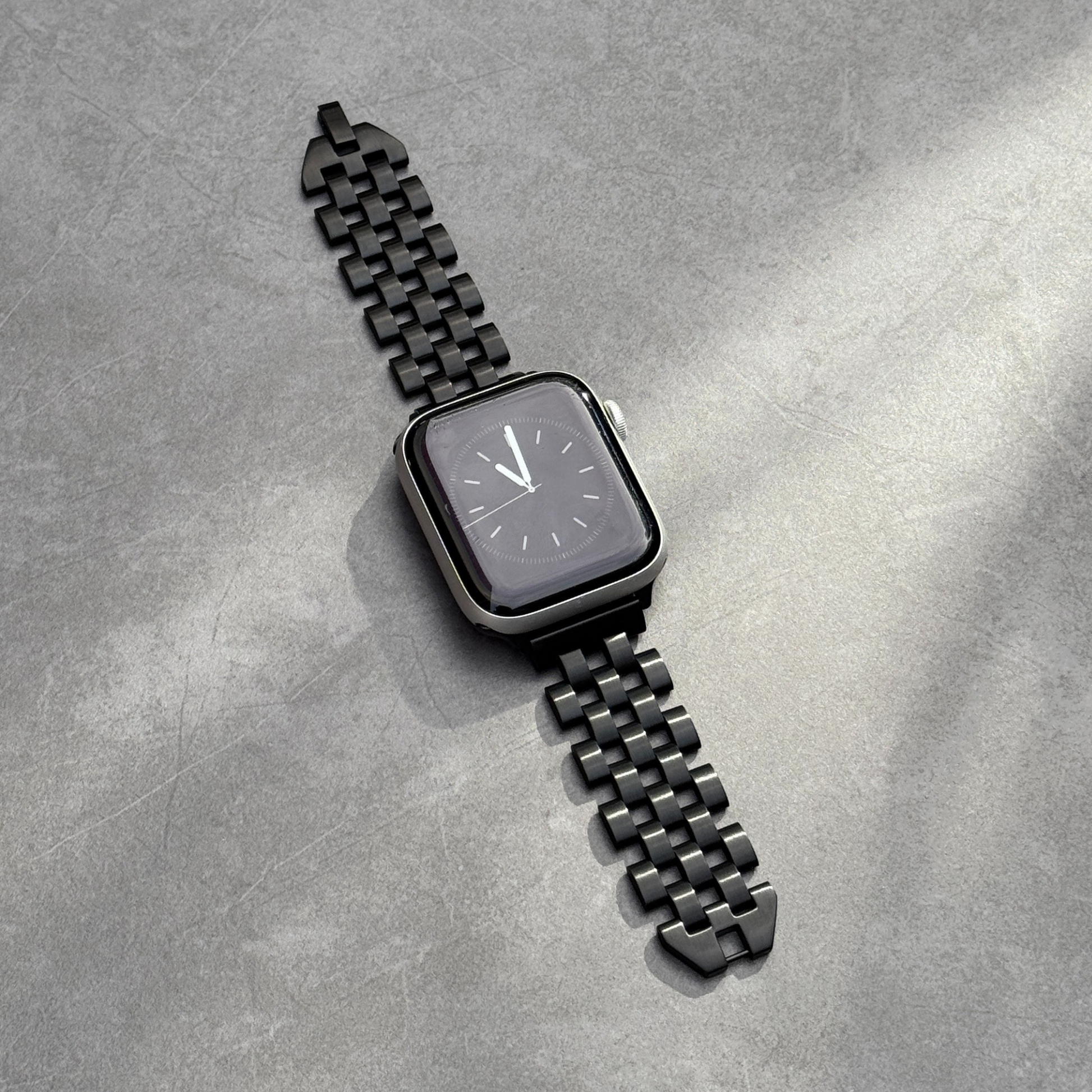 Black smartwatch with a metallic band on a gray textured surface