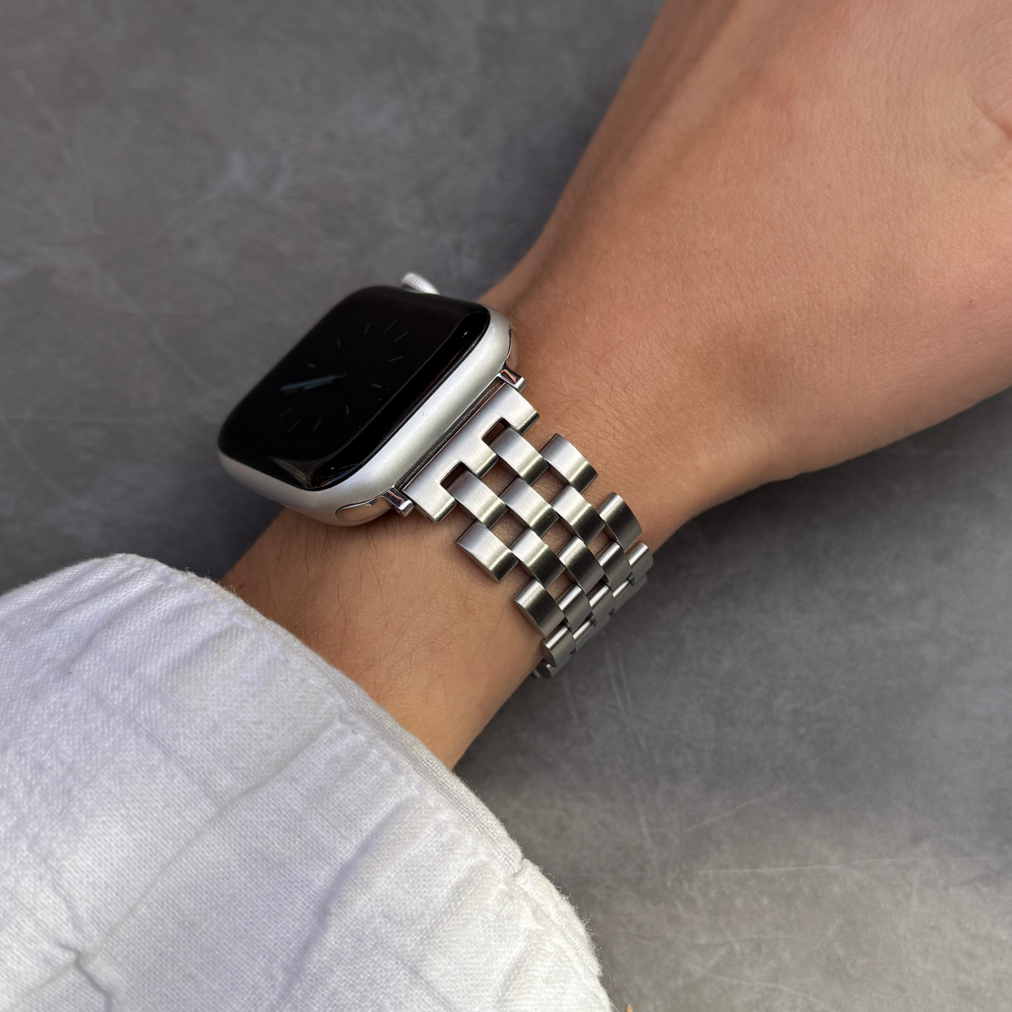 Smartwatch with a metal band on a wrist against a gray background