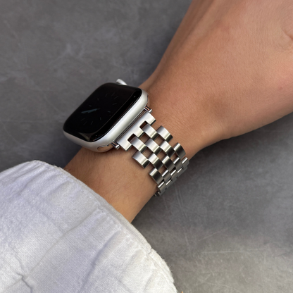 Smartwatch with a metal band on a wrist against a gray background