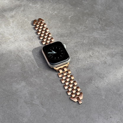 Smartwatch with a rose gold metal band on a gray surface
